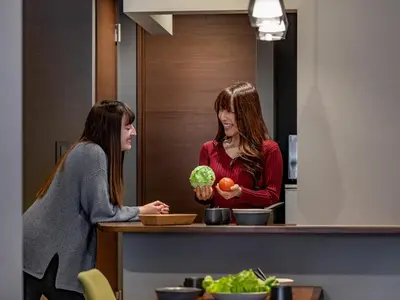 two women standing in a kitchen preparing food at COCOSHUKU Shinjuku-Hanazono in Tokyo