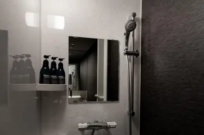 a bathroom with a mirror and bottles of wine at COCOSHUKU Shinjuku-Hanazono in Tokyo