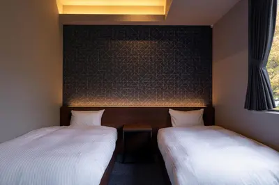 two beds in a room with a wall at COCOSHUKU Shinjuku-Hanazono in Tokyo