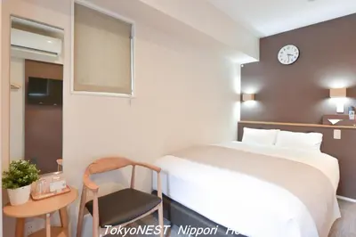 a bedroom with a bed and a chair and a clock at TokyoNEST Nippori in Tokyo