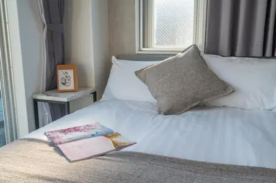 a book sitting on a bed with a window at ZAITO Tokyo Mukojima Hotel \u62bc\u4e0a\u99c5\u5f92\u6b69\u4e03\u5206\u30db\u30c6\u30eb in Tokyo