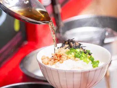 a person pouring food into a bowl of rice at APA Hotel Ueno Ekiminami in Tokyo