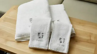 three towels sitting on top of a wooden table at Via Inn Shinagawa Oimachi in Tokyo