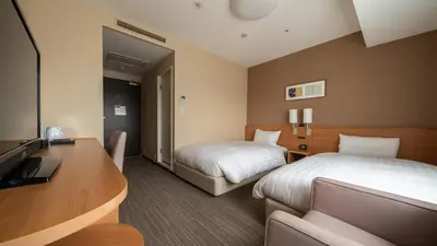 a hotel room with two beds and a desk at Via Inn Shinagawa Oimachi in Tokyo