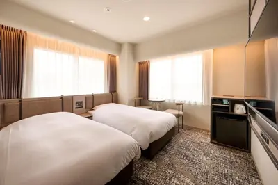 two beds in a hotel room with windows at Via Inn Shinjuku in Tokyo