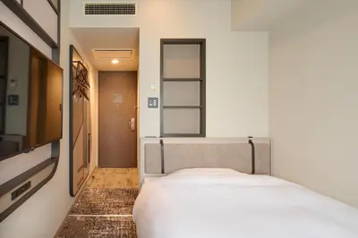 a small bedroom with a bed and a tv at Via Inn Shinjuku in Tokyo