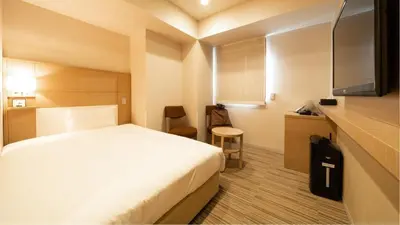 a hotel room with a white bed and a desk at Via Inn Higashi-Ginza in Tokyo