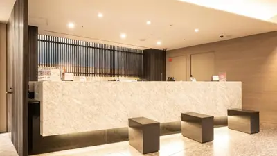 a lobby with a reception counter and two stools at Via Inn Higashi-Ginza in Tokyo