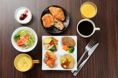 a table with plates of food and a cup of coffee at Via Inn Akihabara in Tokyo