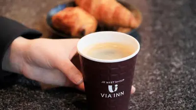 a person holding a cup of coffee on a table at Via Inn Akihabara in Tokyo
