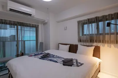 a bedroom with a large white bed and two windows at japan house sugamo in Tokyo