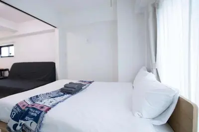 a bedroom with a white bed and a chair at japan house sugamo in Tokyo