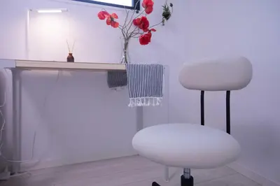 a white desk with a chair and a vase with flowers at japan house sugamo in Tokyo