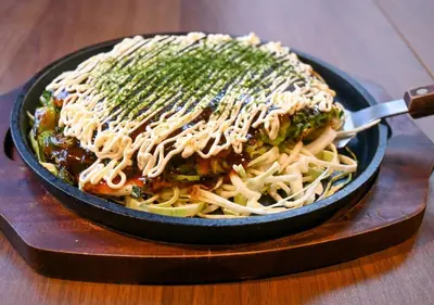 a pan of pasta with sauce and greens on a table at APA Hotel Asakusa Shin Okachimachi Ekimae in Tokyo