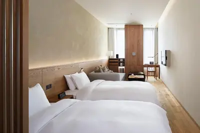 two beds in a hotel room with white sheets at MUJI HOTEL GINZA in Tokyo