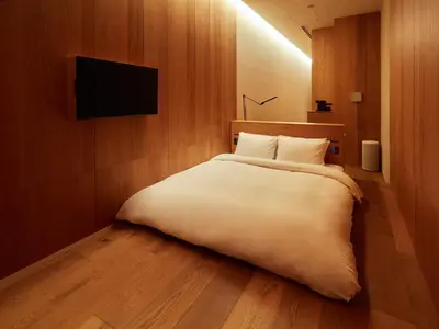 a bedroom with a large white bed with a flat screen tv at MUJI HOTEL GINZA in Tokyo