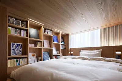 a bedroom with a large bed and book shelves at MUJI HOTEL GINZA in Tokyo
