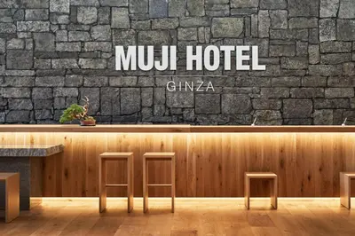a restaurant with two stools in front of a brick wall at MUJI HOTEL GINZA in Tokyo