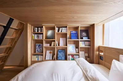 a bed in a room with a book shelf at MUJI HOTEL GINZA in Tokyo