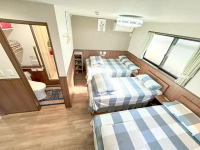 a hotel room with three beds and a bathroom at SHINJUKU WARM VILLA I in Tokyo
