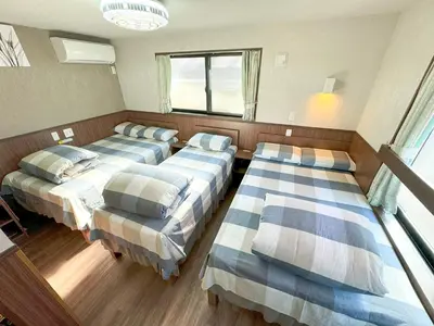 a room with three beds and a window at SHINJUKU WARM VILLA I in Tokyo