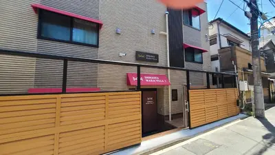 a building with wooden doors on a street at SHINJUKU WARM VILLA I in Tokyo