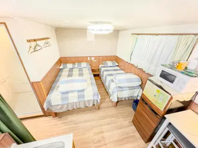 a small room with three beds and a tv at SHINJUKU WARM VILLA I in Tokyo
