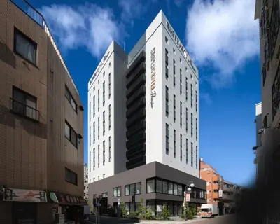a tall white building on a city street at Super Hotel Premier Ikebukuro Natural Hot Spring in Tokyo