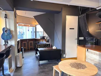 a room with a table and a guitar on the wall at STAY WORK ASAKUSA guest house \u6d45\u8349\u5e97 in Tokyo