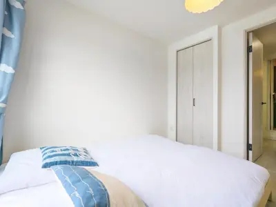 a bedroom with a white bed with a blue curtain at japan house itabashi in Tokyo