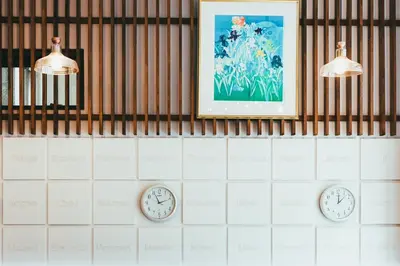 two clocks on a wall with a picture on the wall at Hostel JAZ in Tokyo