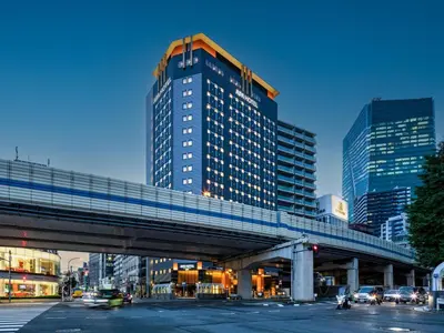 a tall building with a bridge over a city street at APA Hotel & Resort Roppongi Ekihigashi in Tokyo