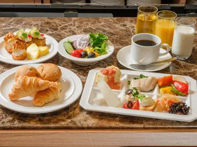 a table with plates of food and a cup of coffee at APA Hotel & Resort Roppongi Ekihigashi in Tokyo
