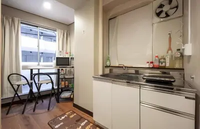 a kitchen with white cabinets and a table with chairs at AN HOTEL in Tokyo