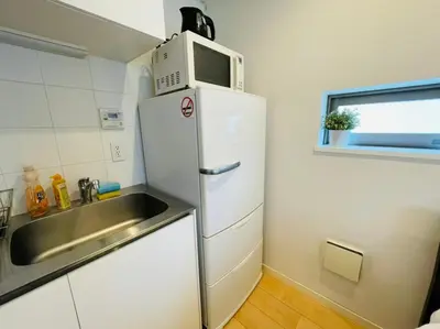 a kitchen with a sink and a microwave on top of a refrigerator at SALON\u6e0b\u8c375B in Tokyo