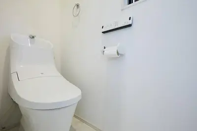 a white toilet in a bathroom with a roll of toilet paper at Shinkoiwa house at JR line.Easy to airport&Disney. in Tokyo