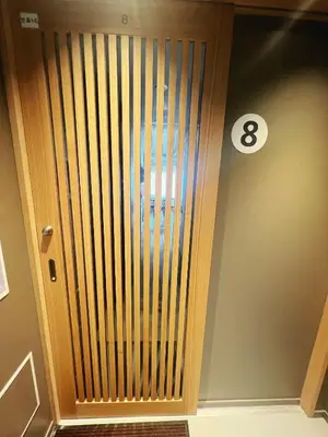 a wooden door in a room with a clock on the wall at Nplus Tokyo Akihabara Premium in Tokyo