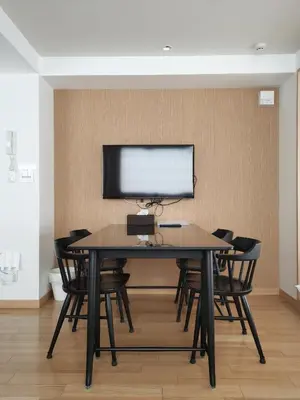 a table with chairs and a monitor on a wall at Nplus Tokyo Akihabara Premium in Tokyo