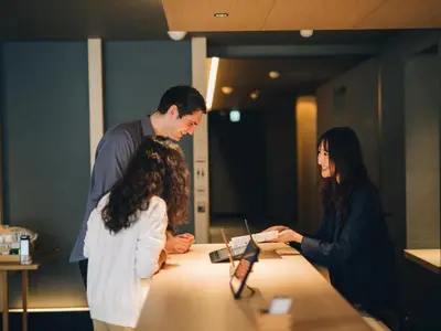 a man and woman standing around a table with a laptop at MIMARU SUITES Tokyo Nihombashi in Tokyo