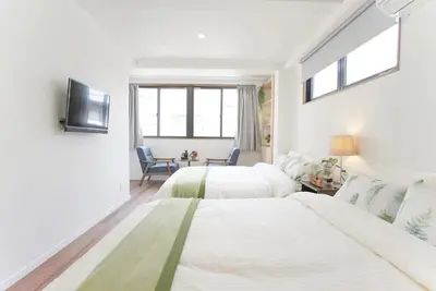 a white bedroom with two beds and a tv at dandelion house in Tokyo