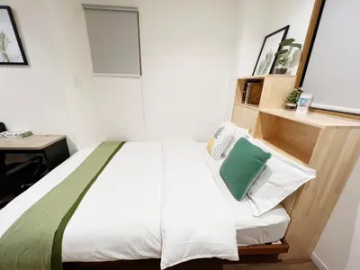 a bedroom with a bed with a green pillow on it at dandelion house in Tokyo