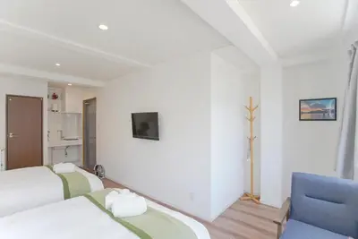 a bedroom with two beds and a blue chair at dandelion house in Tokyo
