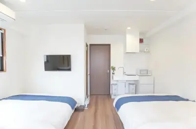 a white room with two beds and a kitchen at dandelion house in Tokyo