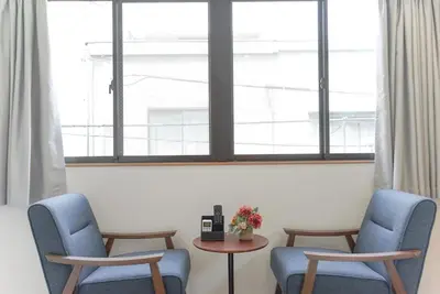two chairs and a table in a room with windows at dandelion house in Tokyo