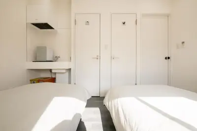 two beds in a bedroom with white cabinets at ZAITO Tokyo Skytree-Yokokawa II Studio \u5929\u7a7a\u6811\u65c1\u8212\u9002\u578b\u6c11\u5bbf-\u5b85\u4e1c\u6a2aII\u53f7\u5e97 in Tokyo
