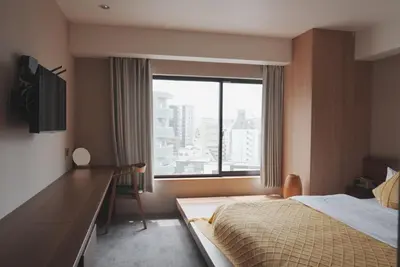 a bedroom with a bed and a desk and a window at ICHIYU HOTEL ASAKUSA in Tokyo