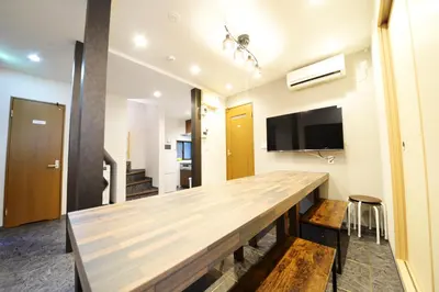 a long wooden table in a room with a tv at NY Cottage B in Tokyo