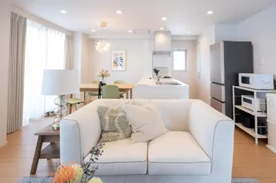 a living room with a white couch and a kitchen at Ken's Place麻布East in Tokyo