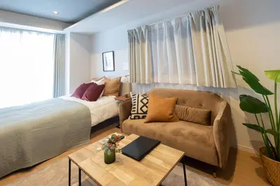 a bedroom with a bed and a couch and a table at Ken's Place麻布East in Tokyo