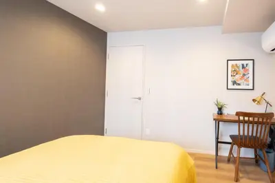 a bedroom with a yellow bed and a desk at Ken's Place麻布East in Tokyo
